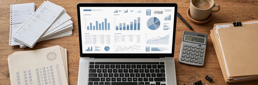Laptop showing financial dashboards next to a calculator and receipts